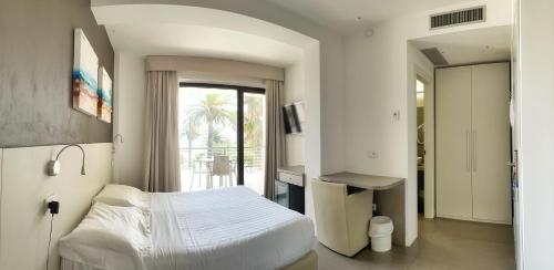 a bedroom with a white bed and a balcony at Hotel Arlecchino in San Benedetto del Tronto