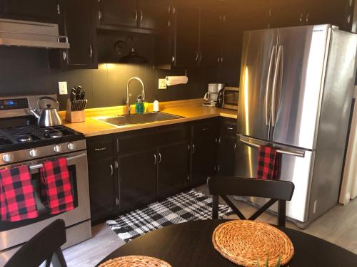 uma cozinha com armários pretos e um frigorífico de aço inoxidável em Maison Solange-Red Barn Farmhouse Style- Moonridge em Big Bear Lake