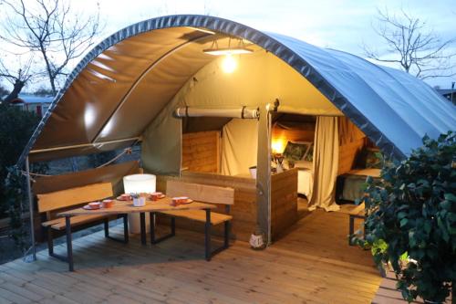 une tente avec des bancs et une table devant elle dans l'établissement Camping Ushuaïa Villages Le Viaduc, à Arlebosc