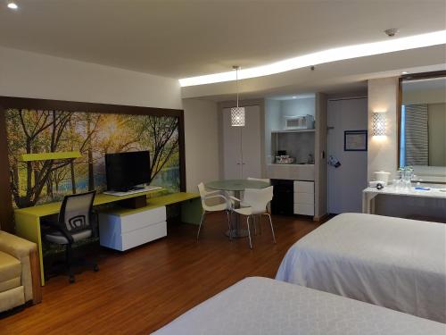 a bedroom with a bed and a table and a kitchen at BelAir Business a Wyndham Garden Hotel in Mexico City