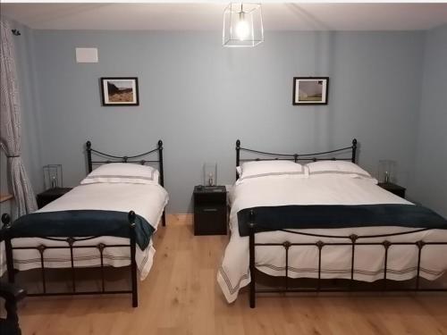 Loughcrew View Bed and Breakfast في كيلز: سريرين في غرفة بجدران بيضاء وأرضية خشبية