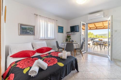 a bedroom with a bed with red pillows and a balcony at Apartment Vesna in Milna