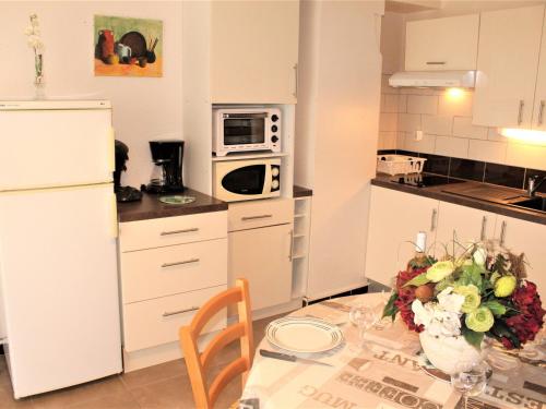 une cuisine avec une table avec un vase de fleurs dessus dans l'établissement Appartement avec Jardinet Privatif à Balaruc-les-Bains, près des Thermes - Classé ⭐⭐ - FR-1-503-51, à Balaruc-les-Bains