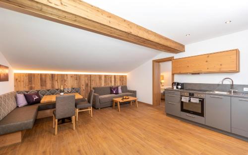 a kitchen and living room with a couch and a table at Das Grünholz Aparthotel in Mühlbach am Hochkönig