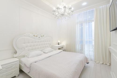 ein weißes Schlafzimmer mit einem weißen Bett und einem Kronleuchter in der Unterkunft 10353 Residential complex Central Park cozy apartment in Kiew