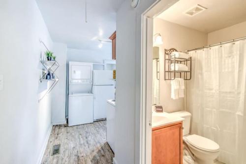 a bathroom with a toilet and a sink and a refrigerator at Walk to the Best of Midtown Charming Cottage in Memphis