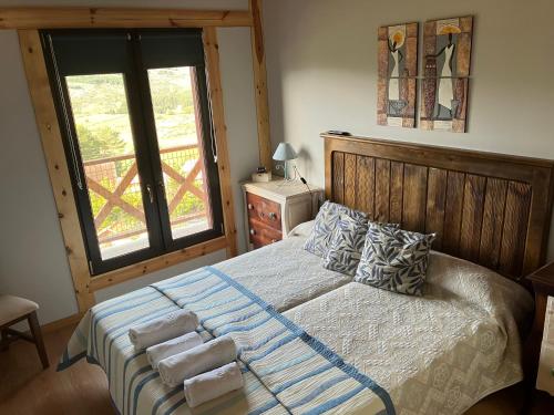 ein Schlafzimmer mit einem Bett mit Kissen und einem Fenster in der Unterkunft Cara norte de Gredos in Hoyos del Espino