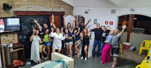 a group of people standing in a room with their hands in the air at Hostel Praia 102 in Ubatuba