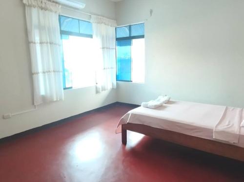 Cette chambre blanche dispose d'un lit et de deux fenêtres. dans l'établissement RESIDENCIA TUKITUKI CASA HERMOSA IQUITOS AMAZONIA, à Iquitos
