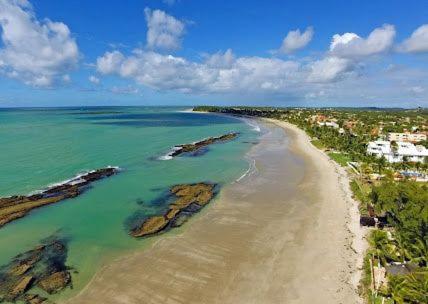 Praia dos carneiros flat hotel في تامانداري: اطلالة جوية على شاطئ به صخور والمحيط