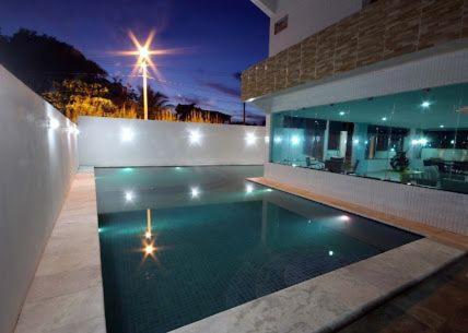 Praia dos carneiros flat hotel في تامانداري: مسبح امام مبنى في الليل