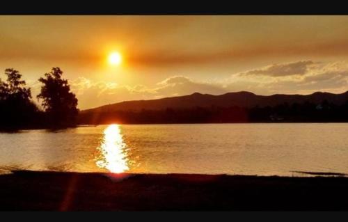 um pôr-do-sol sobre um lago com o pôr-do-sol em Casa Embalsina em Villa del Dique