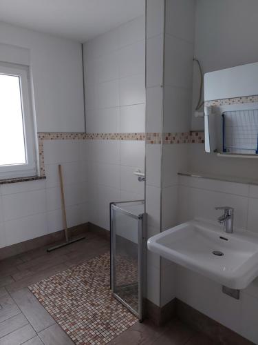a white bathroom with a sink and a window at Ferienwohnung-Havelsee in Hohenferchesar