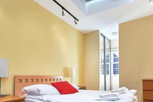 um quarto com uma cama com uma almofada vermelha em Lovely 2 - bedroom London Bridge apartment em Londres