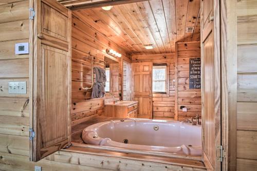 een badkamer met een bad in een kamer met houten wanden bij Upscale Sevierville Retreat with Deck and Hot Tub! in Sevierville