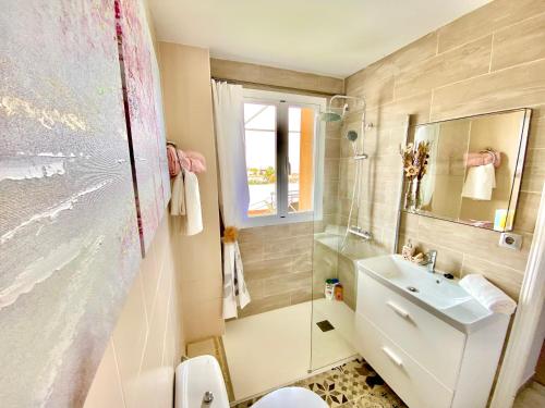 een badkamer met een wastafel, een toilet en een spiegel bij Precioso Ático con las mayores vistas de Sevilla in Tomares