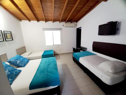 1 Schlafzimmer mit 2 Betten und einem Flachbild-TV in der Unterkunft Hotel Quinta Avenida in Medellín