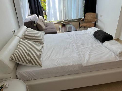 una cama blanca con almohadas en una habitación en דירת סטודיו דקה מחוף הים בת״א, en Tel Aviv