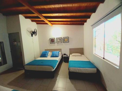 a bedroom with two beds and a large window at Hotel Quinta Avenida in Medellín