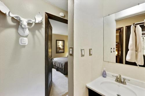 ein Bad mit einem Waschbecken, einem Spiegel und einem Bett in der Unterkunft Tannhauser 121 in Breckenridge
