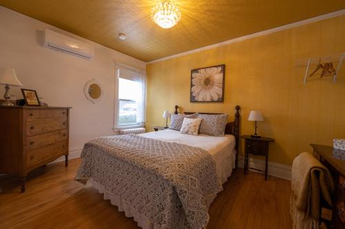 ein Schlafzimmer mit einem Bett, einer Kommode und einem Fenster in der Unterkunft À Tout Venant B&B in Magog-Orford