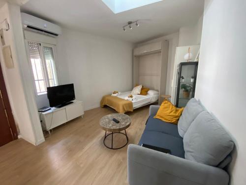 sala de estar con sofá azul y TV en Bonito Estudio con terraza, en Madrid