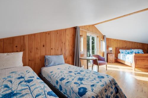 a bedroom with two beds and a table with a chair at MontFJORD - Chalets, SPA et vue - ChantaFJORD #1 in Sacré-Coeur-Saguenay