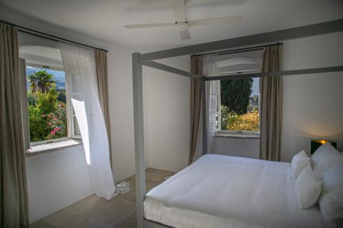a bedroom with a white bed and two windows at Revelin Hvar in Stari Grad