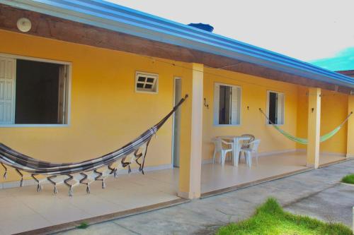 a yellow house with a balcony with a table and chairs at Recanto do Rey in Mucuri