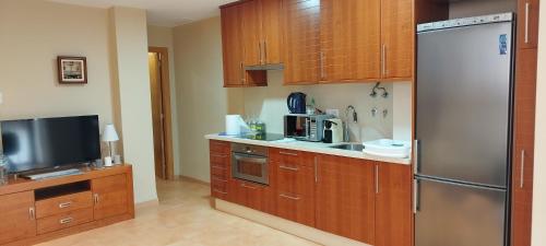 a kitchen with wooden cabinets and a stainless steel refrigerator at Cozy Apartment close to the beach in beatiful area in El Perelló