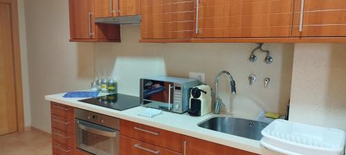 cocina con fregadero y microondas en Cozy Apartment close to the beach in beatiful area, en El Perelló