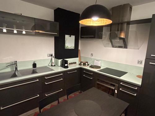 a kitchen with black cabinets and a sink at Spacieux T2 avec parking à 200 m Cathédrale in Chartres