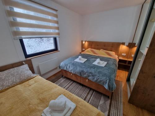 a small bedroom with two beds and a window at Cozy Ski Apartment Jahorina in Jahorina