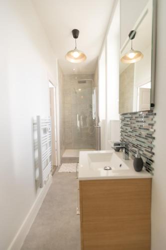 a white bathroom with a sink and a shower at La Porte des Volcans in Blanzat