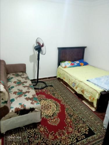 a room with two beds and a couch and a floor fan at Aatun flat in Miami families only in Alexandria