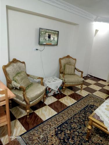 a living room with two chairs and a checkered floor at Aatun flat in Miami families only in Alexandria