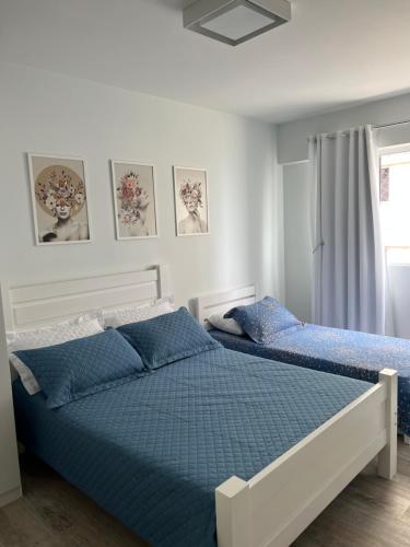 1 dormitorio con 2 camas con sábanas azules y ventana en NOVO Mar Doce Lar Pé na Areia, en Balneário Camboriú