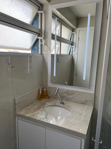La salle de bains est pourvue d'un lavabo et d'un miroir. dans l'établissement NOVO Mar Doce Lar Pé na Areia, à Balneário Camboriú