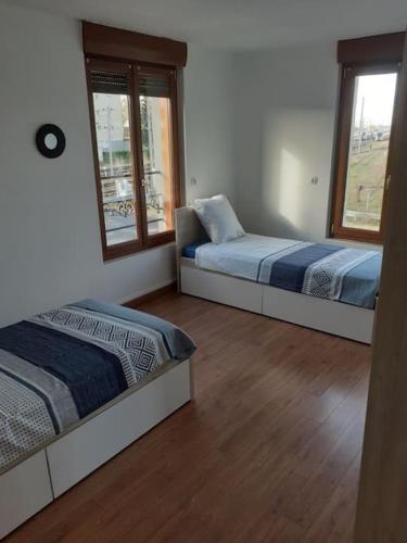 deux lits dans une chambre avec deux fenêtres dans l'établissement Le p’tit Bragard, à Saint-Dizier