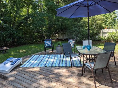 eine Terrasse mit einem Tisch, Stühlen und einem Sonnenschirm in der Unterkunft Wilmington Family Vacation Home in Wilmington