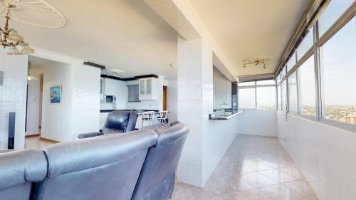 a living room with a couch and chairs and windows at Shangri-La Penthouse View in Kingsburgh