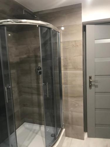 a shower with a glass door in a bathroom at Apartament, noclegi na doby - Raczki k. Suwałk in Raczki