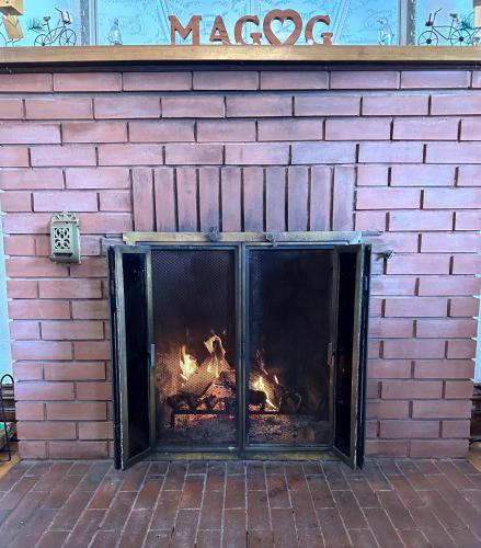 a brick fireplace with a fire in it at À Tout Venant B&B in Magog-Orford