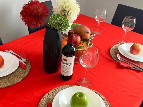 a red table with a bottle of wine and wine glasses at Calle Mora De Rubielos with Free Private Underground Parking in Valencia