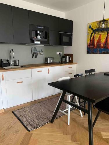 a kitchen with white cabinets and a table with chairs at BOTKa apartmán, Tatranská Štrba in Tatranska Strba
