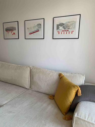a white couch in a living room with pictures on the wall at BOTKa apartmán, Tatranská Štrba in Tatranska Strba