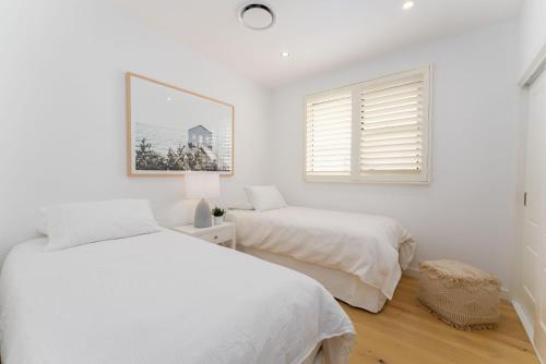 - une chambre blanche avec 2 lits et une fenêtre dans l'établissement Surf Beach House, à Shellharbour