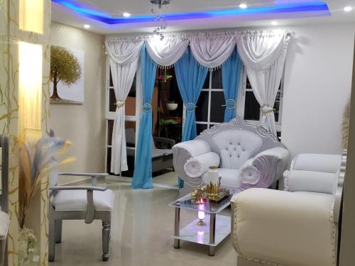 sala de estar con muebles blancos y cortinas azules en Hermoso Apartamento En Cerro Alto Santiago en Santiago de los Caballeros