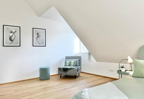 a white bedroom with a chair and a bed at OrestaLiving - Penthouse in 1020 in Vienna