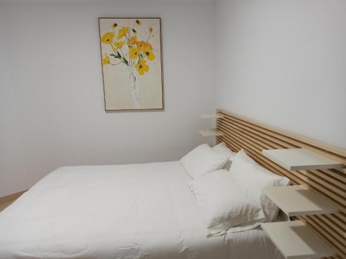 Un dormitorio con una cama blanca y una pintura en la pared en A Casa da Compañía, en Monforte de Lemos
